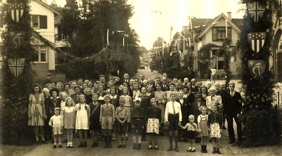 Oude foto met heel veel kinderen en ouders in een straat. 