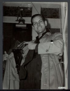 Zwart/wit foto van een man die poseert met een uniform. 